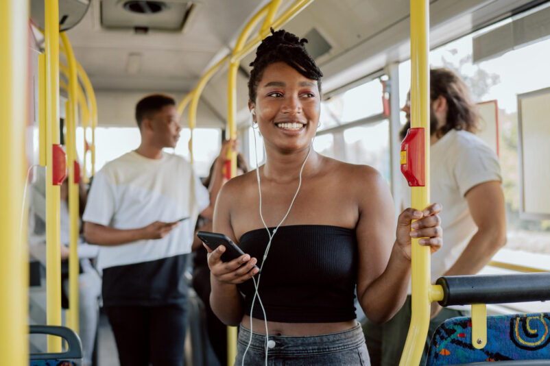 smiling woman good mood rides bus school morning headphones ears listening music